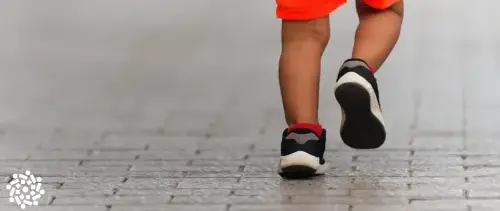 Criança caminha utilizando sapato infantil. Saiba como escolher o modelo ideal