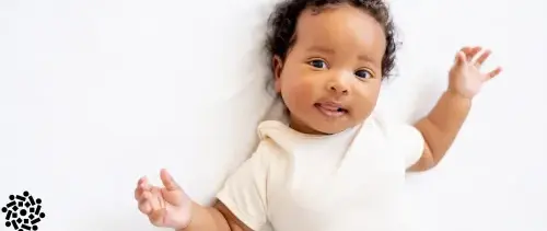 Bebê sorridente deitado na cama. Mortalidade infantil caiu drasticamente desde os anos 1990.