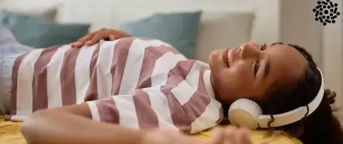 Adolescente deitada escuta música alta no fone de ouvido. Quanto mais alto o som, menor é o tempo considerado seguro.