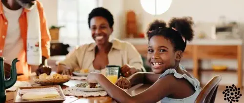 Criança sorridente participa de refeições em família. Estas são oportunidades para aprender pelo exemplo, conversar e criar vínculos