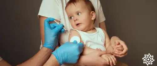 Bebê no colo de sua mãe toma vacina no braço. A vacinação é a principal forma de prevenção contra o sarampo.